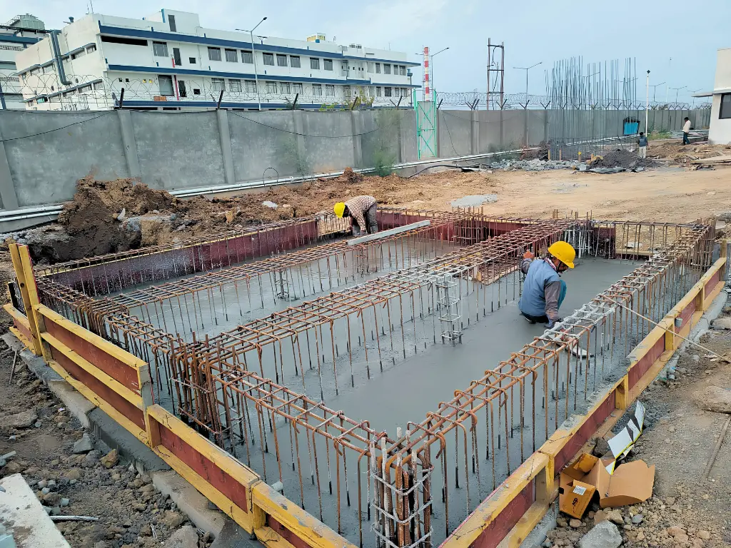 Construction workers setting up RCC structural framework for an industrial foundation.